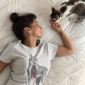 tattooed-girl-wearing-a-t-shirt-mockup-petting-her-cat-on-the-bed-a18791